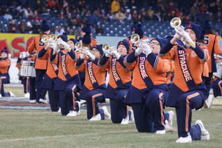 The Syracuse University Marching Band kneels and plays “New York Medley” as part of its pre-game performance. Junior Brendan Malcarne and seniors Riley Moore and Grace Sainsbury held their trumpets with pride as fans watched from the stands. 