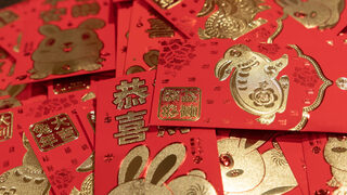 A table is covered in red envelopes and a sign inviting students to take one. Traditionally filled with lucky money and given to children from the elders as a Spring Festival blessing, the envelopes were offered to students to dispel evil and ensure safety. 