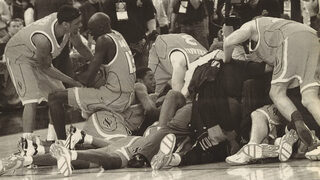 Syracuse Orangemen players and coaches pile onto the floor moments after defeating the Kansas Jayhawks in the NCAA men’s basketball national championship on April 7, 2003 in New Orleans.