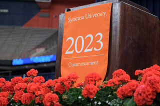 Orange flowers adorn the podium at the commencement ceremony. “You will always be orange,” Syverud said to graduates.  